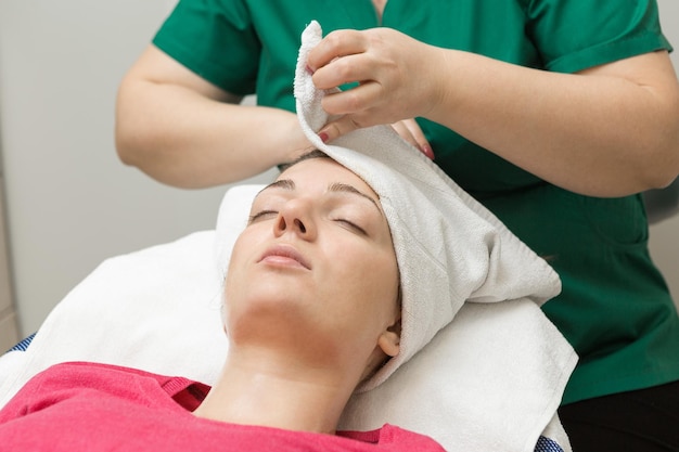 Esthéticienne en soins de la peau du visage appliquant un masque à l'huile de beauté sur le visage à l'aide d'une brosse dans un salon de spa