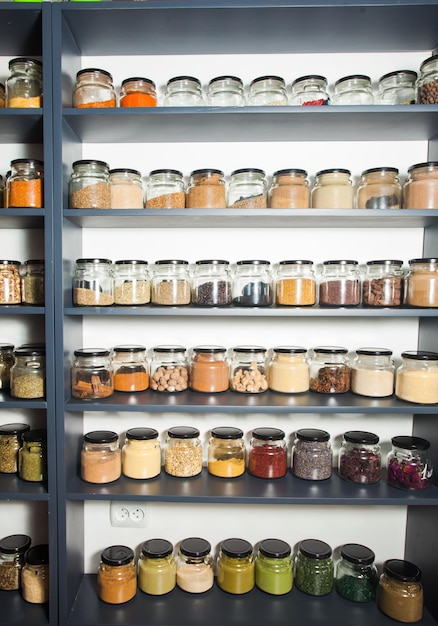 Photo Étagère dans un magasin avec des épices naturelles colorées et des poudres dans des bocaux en verre exposés. fruits secs et noix, céréales dans la boutique. grosery market et alimentation saine et concept zéro déchet