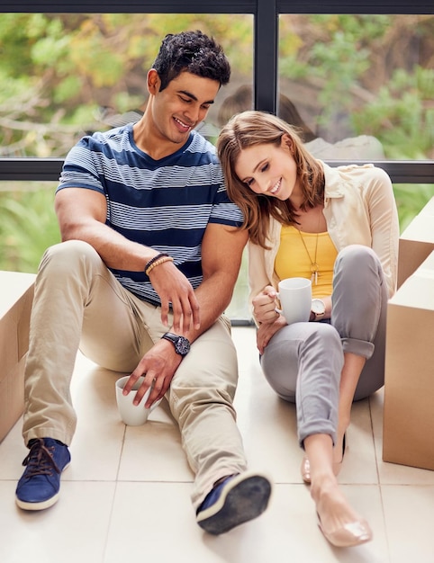 C'était une longue journée de déménagement mais ça valait le coup Photo d'un jeune couple assis par terre tout en faisant une pause avant d'emménager dans une nouvelle maison