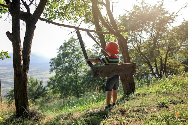 L'été après le verrouillage, un garçon assis seul sur une balançoire dans les montagnes loin du terrain de jeu habituel