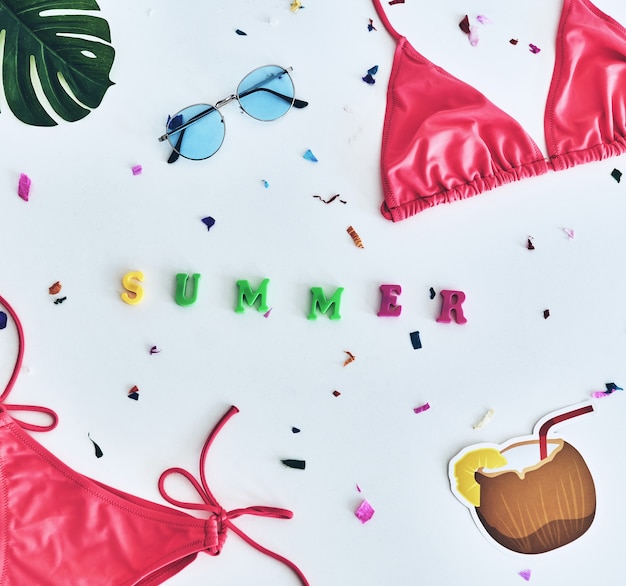 L'été est là! Capture en grand angle du bikini, des lunettes, de la noix de coco et de la fleur allongée contre
