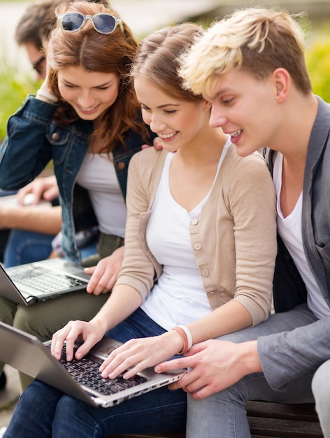 été, internet, éducation, campus et concept d'adolescent - groupe d'étudiants ou d'adolescents avec des ordinateurs portables qui traînent