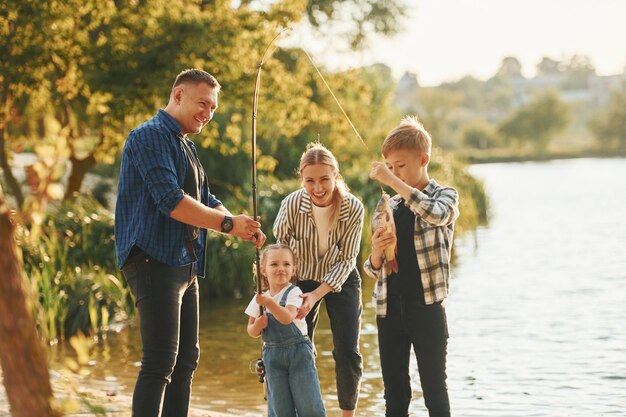 En été, père et mère avec fils et fille sur la pêche ensemble à l'extérieur