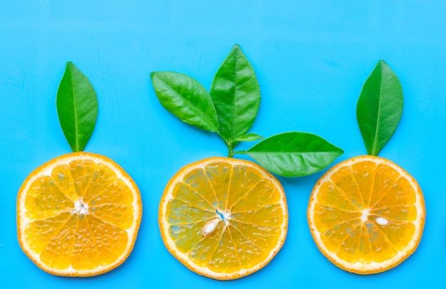 Photo Été de tranche de fruits orange avec des feuilles vertes sur fond bleu.