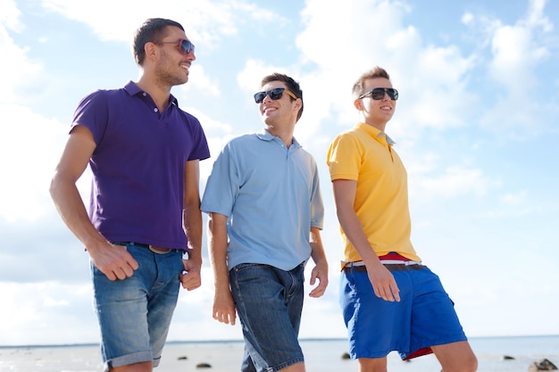 été, vacances, vacances, concept de gens heureux - groupe d'amis masculins marchant sur la plage