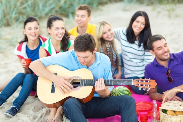 été, vacances, vacances, musique, concept de gens heureux - groupe d'amis avec guitare s'amusant sur la plage