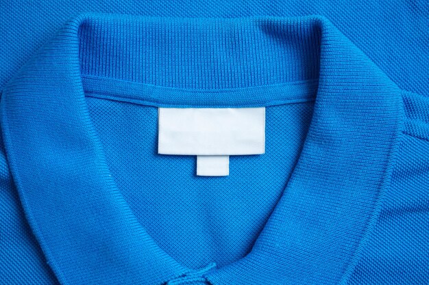 Photo Étiquette blanche de vêtements de blanchisserie sur fond de tissu de chemise bleue