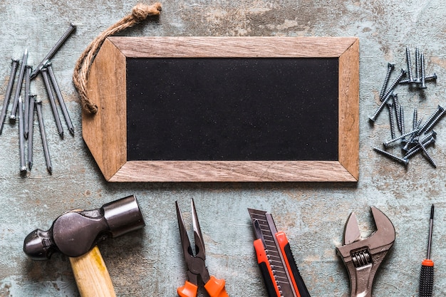 Photo Étiquette en bois blanche avec divers outils de travail sur le bureau en bois rouillé