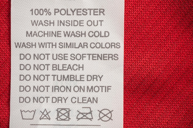 Photo Étiquette de vêtements d'instructions de lavage d'entretien du linge blanc sur une chemise de sport en polyester jersey rouge