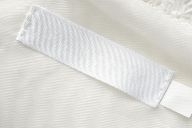 Étiquette De Vêtements De Soin De Lessive Blanche Vierge Sur Fond De Texture De Tissu