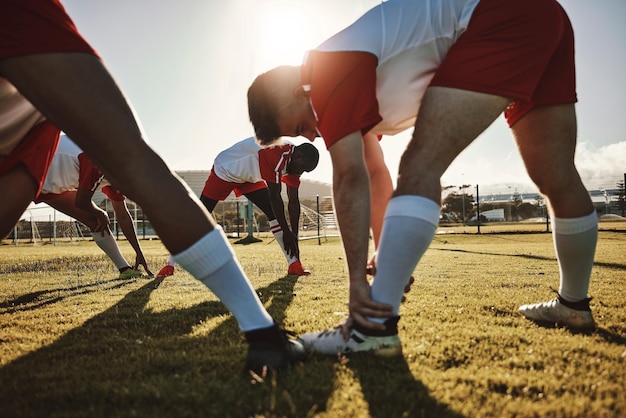 Photo Étirement des jambes et des hommes à l'entraînement de football sur un terrain pour l'exercice cardio de fitness et la collaboration sportive équipe de joueurs de football faisant un échauffement avant un match de sport dans un parc en été