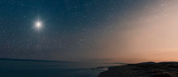 Photo une étoile brille dans le ciel nocturne au-dessus de la mer le jour de noël.