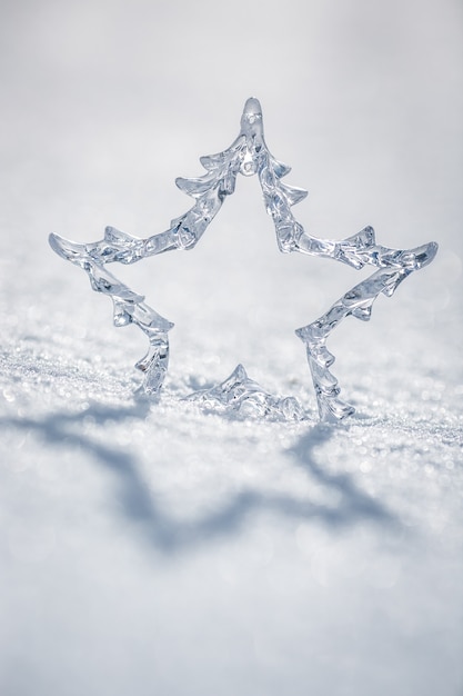 Photo Étoile de noël argentée sur de la vraie neige à l'extérieur. concept de vacances d'hiver. faible profondeur de champs