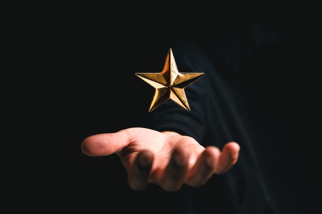 Étoile d'or à portée de main sur fond sombre, évaluation
