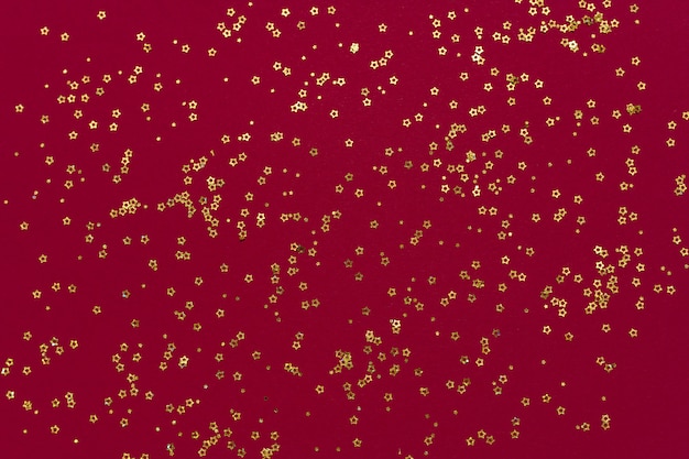 Photo Étoiles de paillettes d'or sur fond rouge foncé