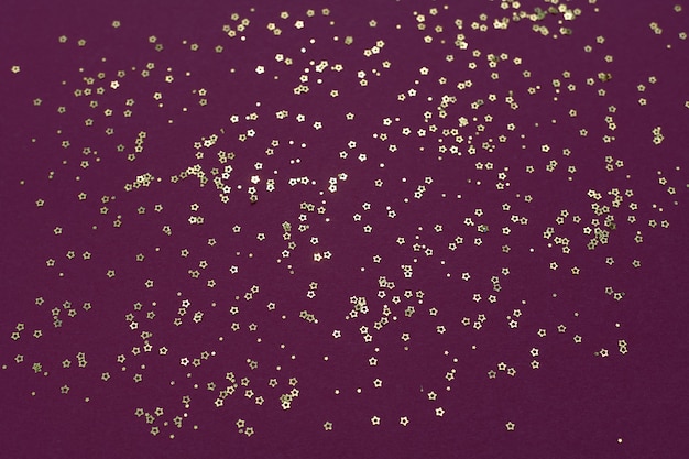Photo Étoiles de paillettes d'or sur fond violet