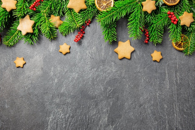 Étoiles de pain d'épice traditionnelles de Noël avec des épices de décoration et des branches d'arbres de Noël sur un fond de pierre sombre Vue de dessus Espace de copie