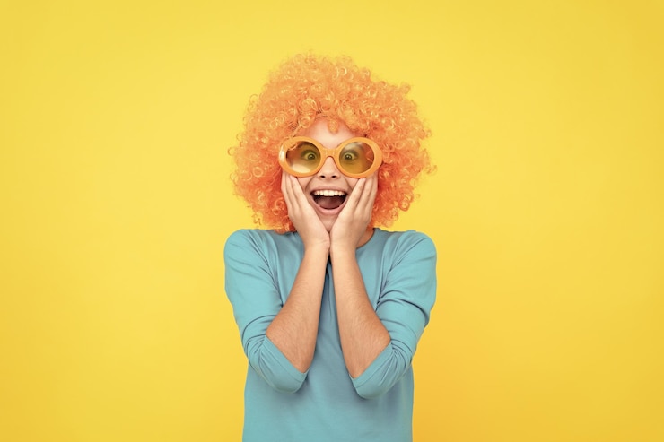Photo étonné enfant fille égoïste en perruque bouclée et lunettes de fête étonnement