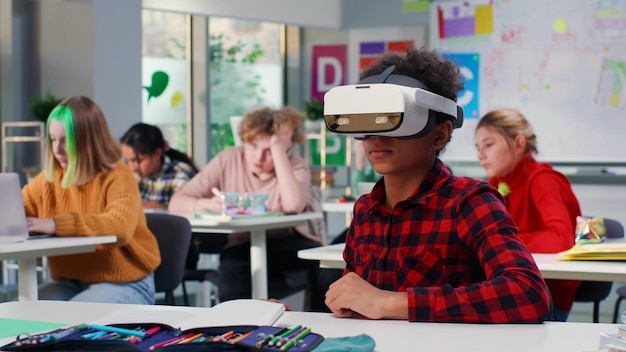 Photo Étudiant adolescent afro-américain s'asseoir et bureau et mettre le casque vr