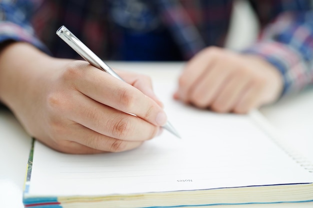 Un étudiant adolescent asiatique écrit des devoirs, étudie une leçon pour un examen, apprend en ligne.