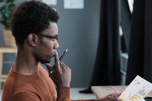 Photo Étudiant africain à lunettes assis avec un regard pensif et se préparant aux examens