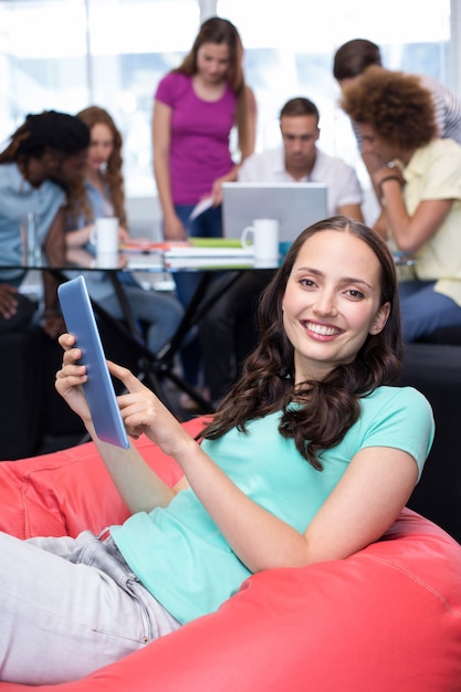 Photo Étudiant à l'aide de tablette numérique avec des amis en arrière-plan