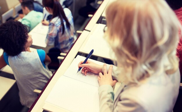 Photo l'étudiant écrivant dans un bloc-notes lors d'un examen ou d'une conférence