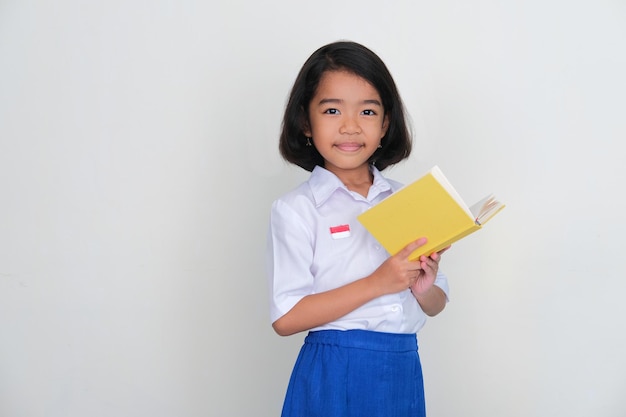 Photo Étudiant enfant indonésien souriant tout en tenant un livre