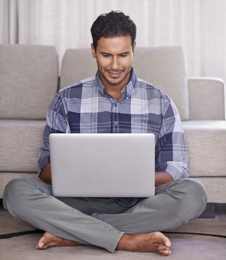 Photo l'étudiant et l'internet pour l'ordinateur portable sur le sol du salon l'éducation et le défilement ou la navigation sur le site web la personne masculine heureuse et en ligne pour l'information ou à la maison pour l'application assise et l'apprentissage électronique sur la technologie