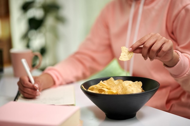 Un étudiant mange des frites en faisant ses devoirs.