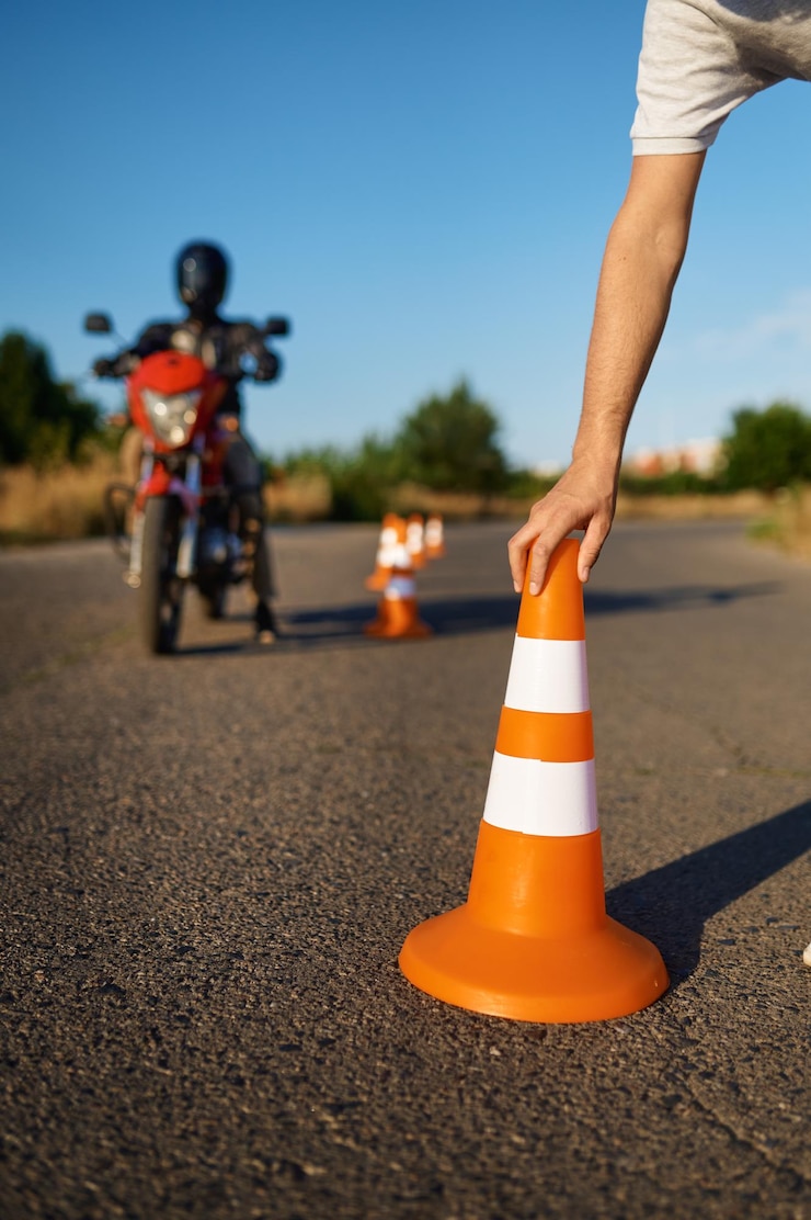 Photo étudiant masculin en casque et instructeur, serpent à cheval entre les cônes à l'école de moto. formation des motards débutants