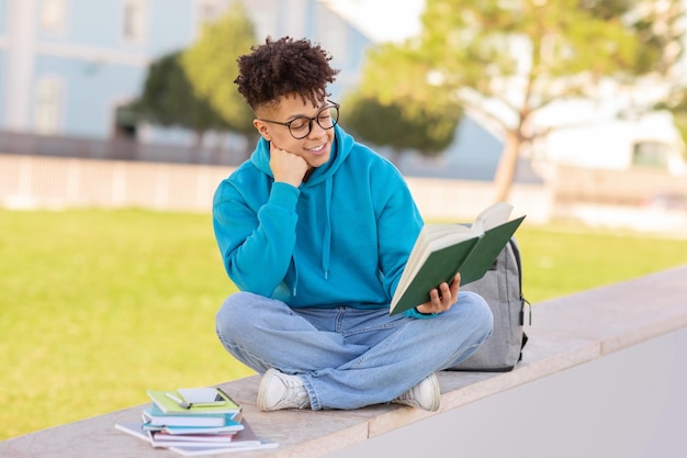 Un étudiant réfléchi avec un crayon et un livre qui étudie dans le parc.