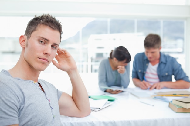 Un étudiant regardant sérieusement avec sa main sur sa tête regarde dans la caméra