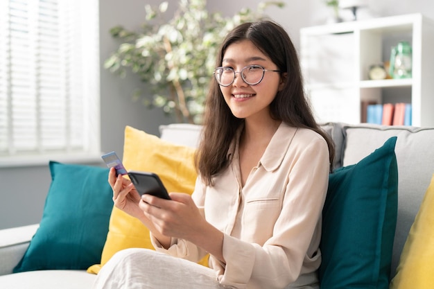 Un étudiant satisfait avec des lunettes et une beauté asiatique repose dans un dortoir sur le canapé regarde la caméra