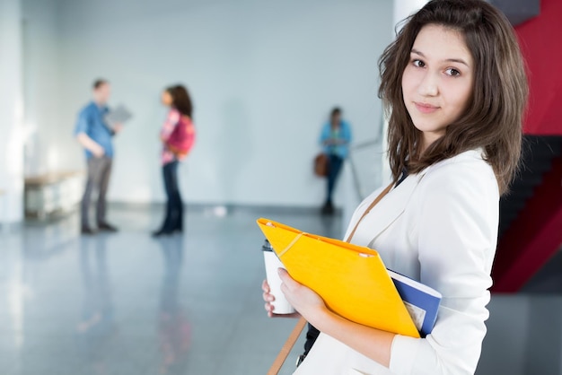 Un étudiant se tient dans un couloir avec d'autres étudiants en arrière-plan.