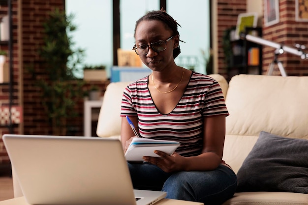 Étudiant sérieux à distance regardant un didacticiel éducatif, assistant à des cours en ligne, prenant des notes. Apprentissage en ligne, enseignement à domicile, cours universitaire à distance, femme écrivant dans un cahier