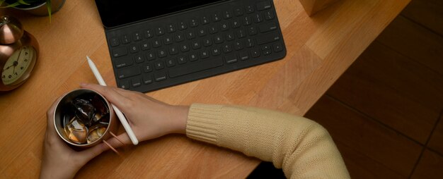 Un étudiant tenant une tasse de café glacé tout en faisant un devoir