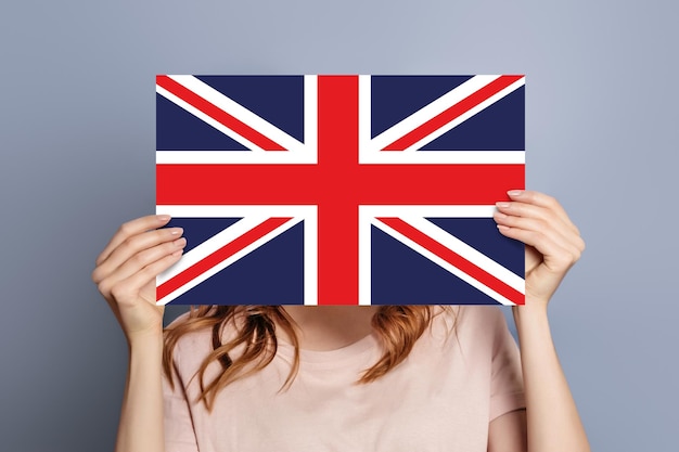 L'étudiant tient le drapeau du Royaume-Uni, l'emblème du discours, la bulle isolée sur le fond gris du studio.