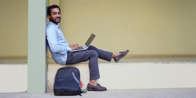 Un étudiant universitaire apprend des leçons en ligne tout en étant assis sur le campus universitaire