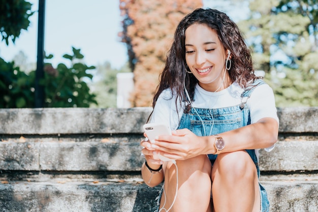 L'étudiant utilise un téléphone intelligent sur le campus pour vérifier ses notes sur l'examen et les nouvelles tout en écoutant de la musique. Jeune femme africaine utilisant des vêtements en denim à la mode, heureuse de ce qu'elle lit au téléphone.