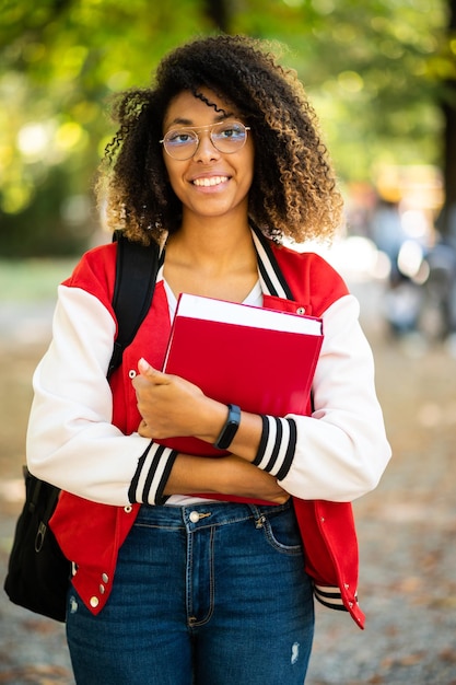 Photo Étudiante africaine tenant un livre dans un parc universitaire