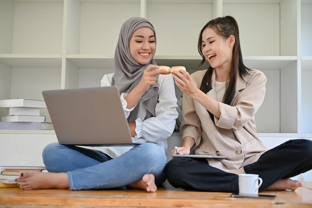 Une étudiante asiatique au café avec son amie musulmane aime parler et manger des beignets