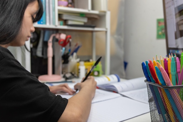 Une étudiante asiatique écrit ses devoirs et lit un livre au bureau