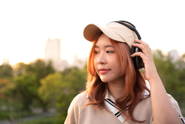 Une étudiante asiatique heureuse aime écouter de la musique avec un casque après les cours au parc naturel de la ville