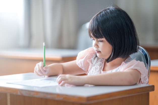 Une étudiante asiatique se concentre sur l'écriture sur le papier d'examen dans la classe