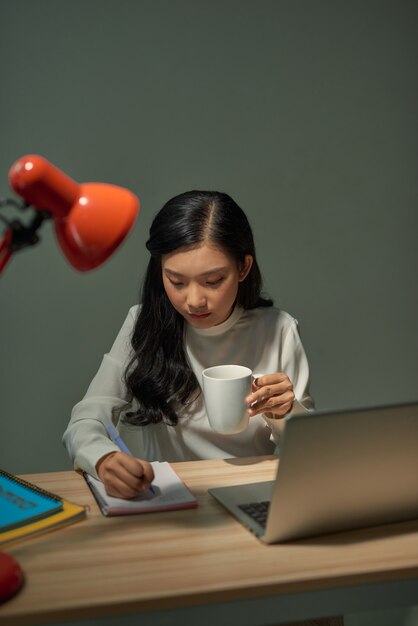 Une étudiante asiatique utilise l'ordinateur portable le soir