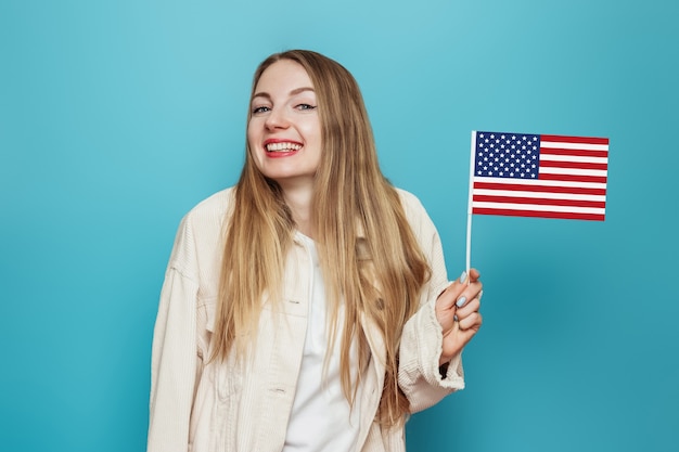 étudiante blonde tient un petit drapeau américain et sourit