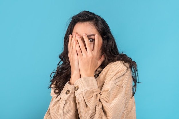 Une étudiante brune caucasienne du millénaire effrayée en tenue décontractée se couvre le visage avec les mains