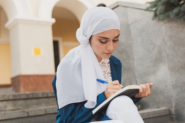 Une étudiante du Moyen-Orient est assise dans les escaliers de l'éducation et des connaissances du campus universitaire