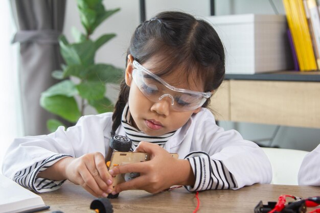 Étudiante fabriquant des voitures robotiques Une fille à l'école de robotique rend le robot géré par le constructeur l'enfant apprend la construction de robots